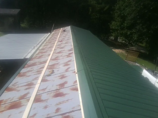 Old rusted panels beside newly installed green metal roofing — Wind Damage Roof Repair by Roofing Brothers in Umatilla
