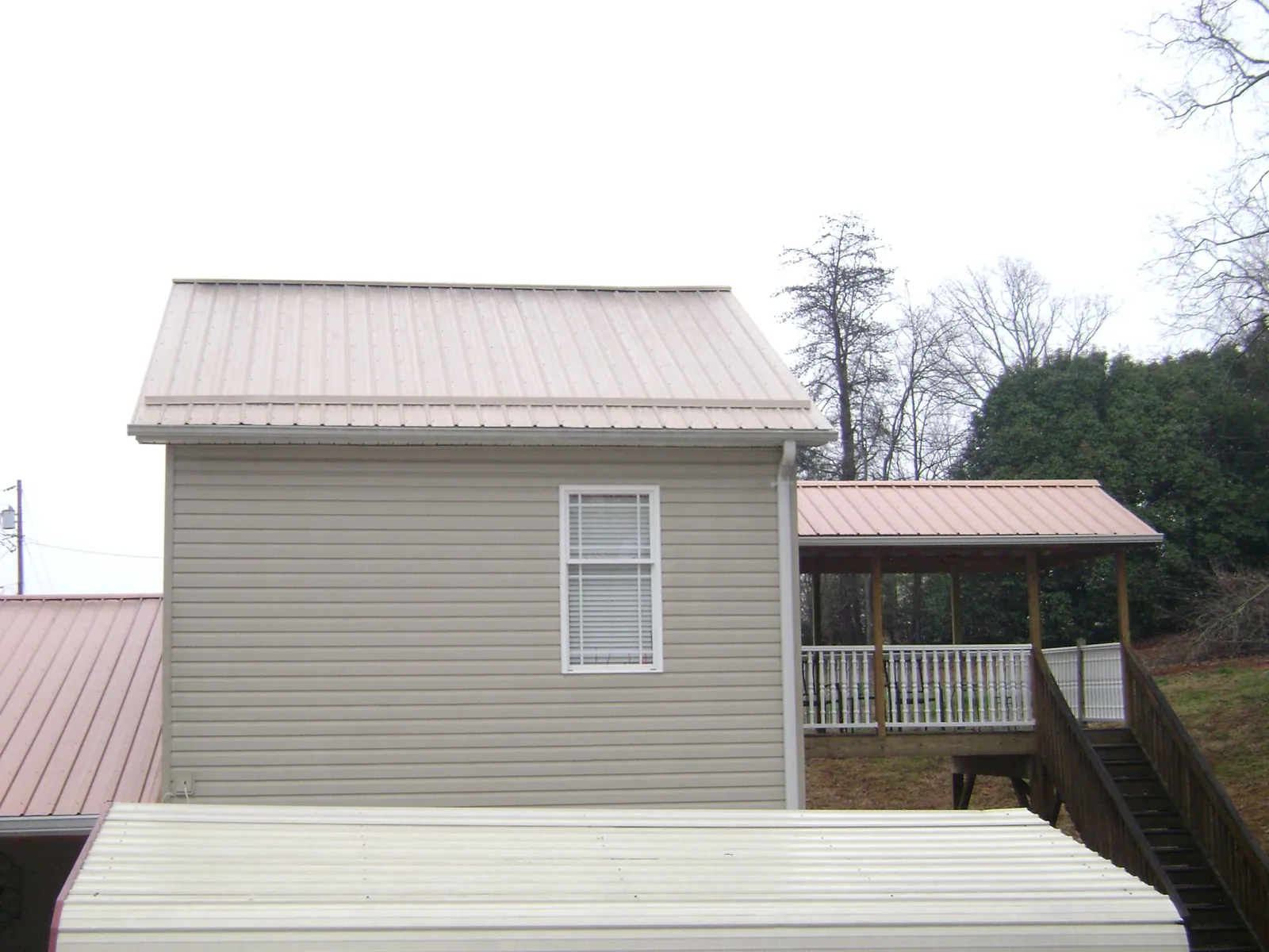 Tan metal roofs on a two story addition and attached porch, from a Roof Replacement job in Umatilla